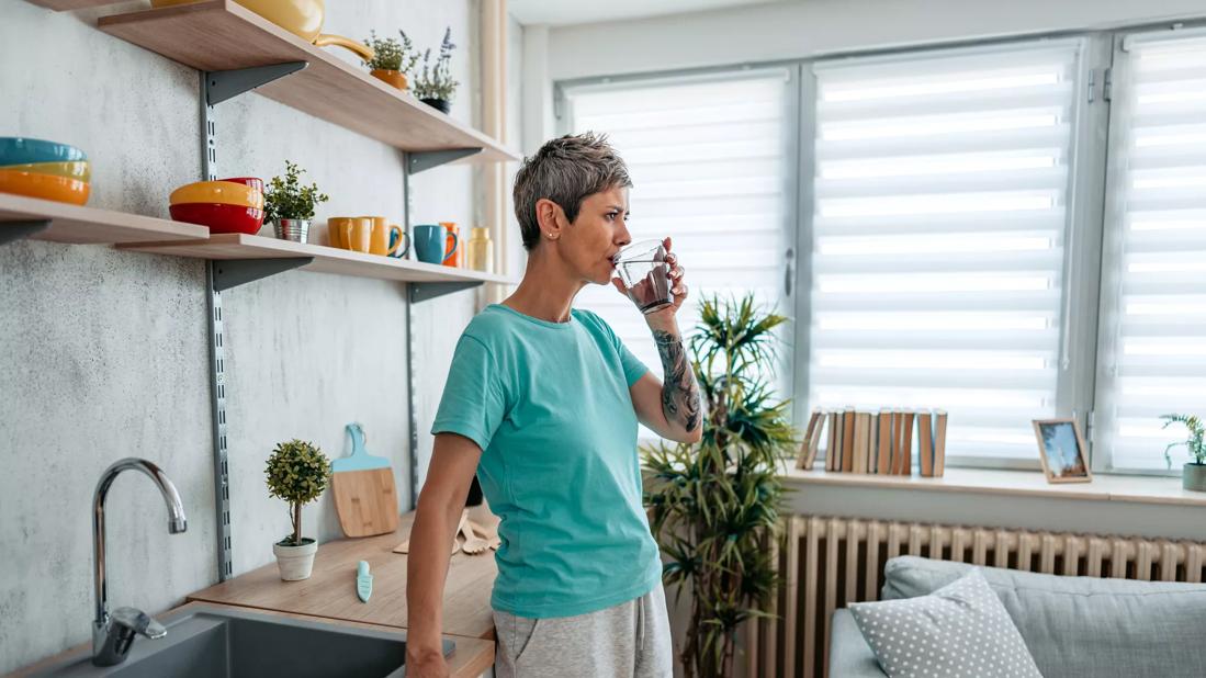 Person in kitchen drinking glass of water