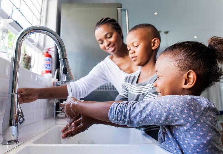 Mom and children wash hands at the sink