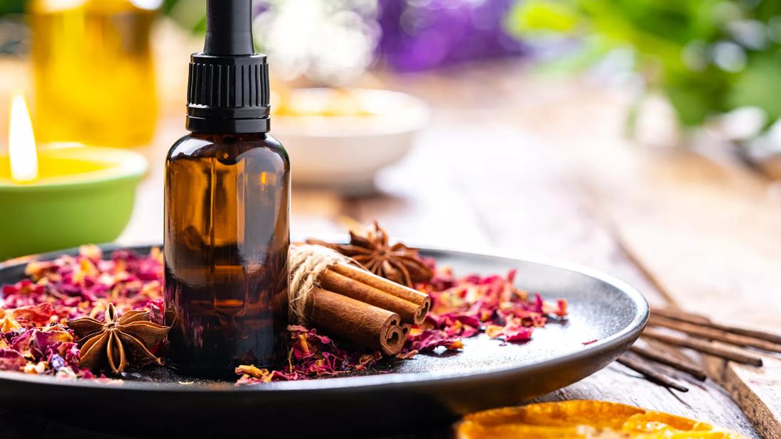 Bottle of essential oil on plate of potpourri, with and candles