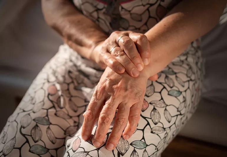 Person rubbing painful wrists and hands on lap.