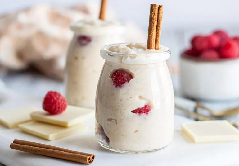 Bread pudding with raspberries in a small glass container with a cinnamon stick