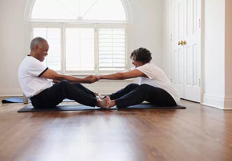 Two people helping each other stretch on floor.