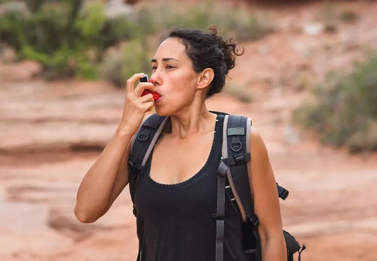 Woman uses inhaler during hike