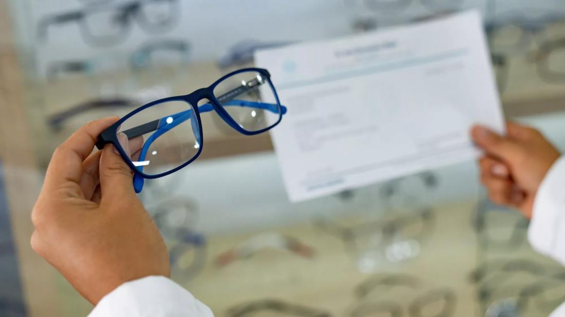 Eye doctor holding glasses and a prescription
