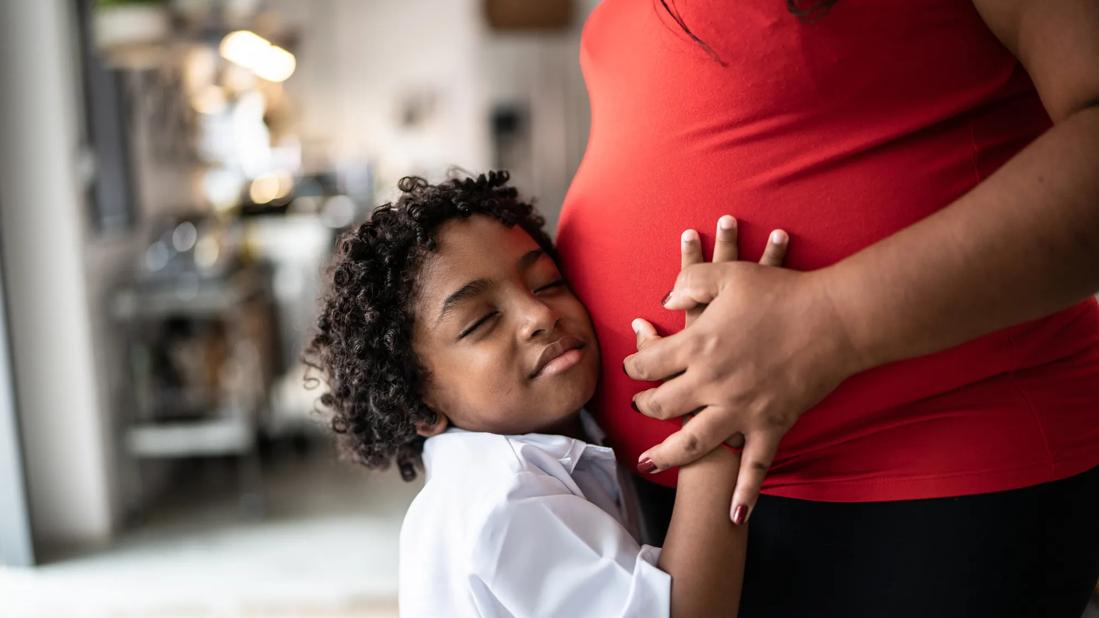 Child hugging mother who is pregnant