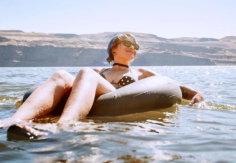 woman sunbathing in river floating on tube