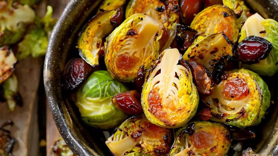 roasted brussel sprouts in bowl with chopped dates and hazelnuts