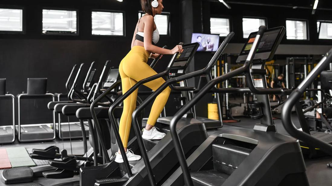 Person dressed in yellow yoda pants with headphones on using stair climber at gym