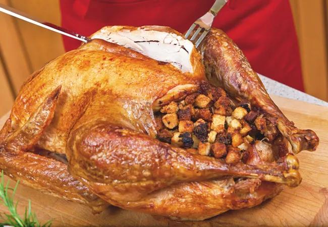 A person skillfully carving a turkey on a wooden cutting board.