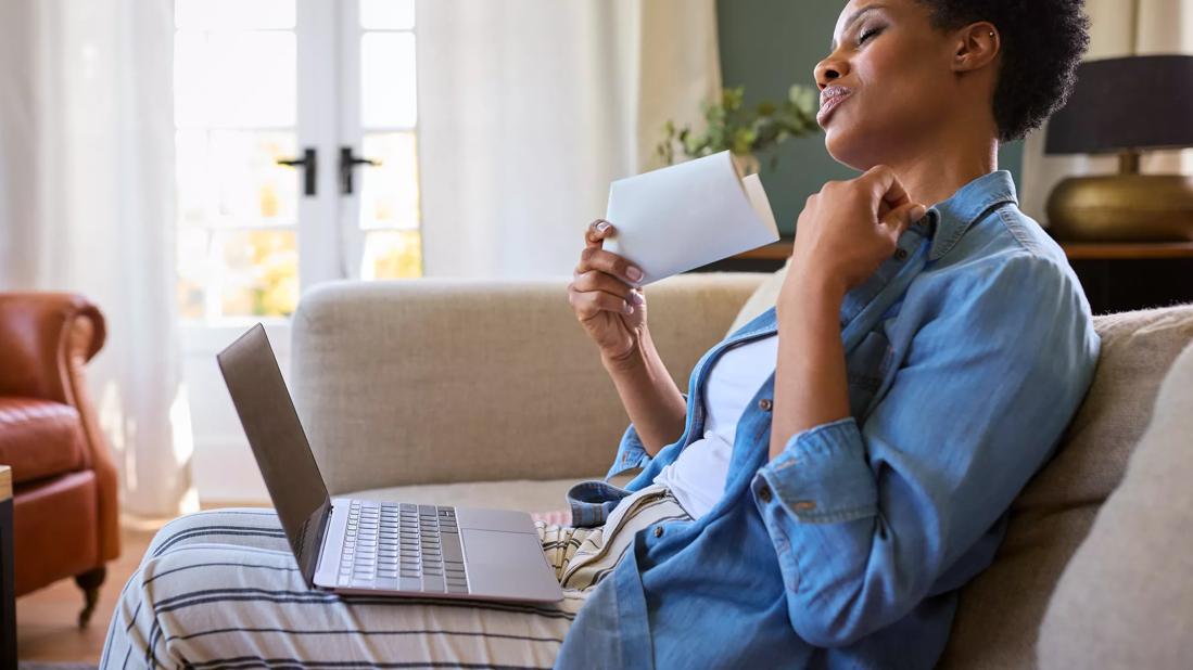 Female sitting on couch at home fanning their face from hot flash