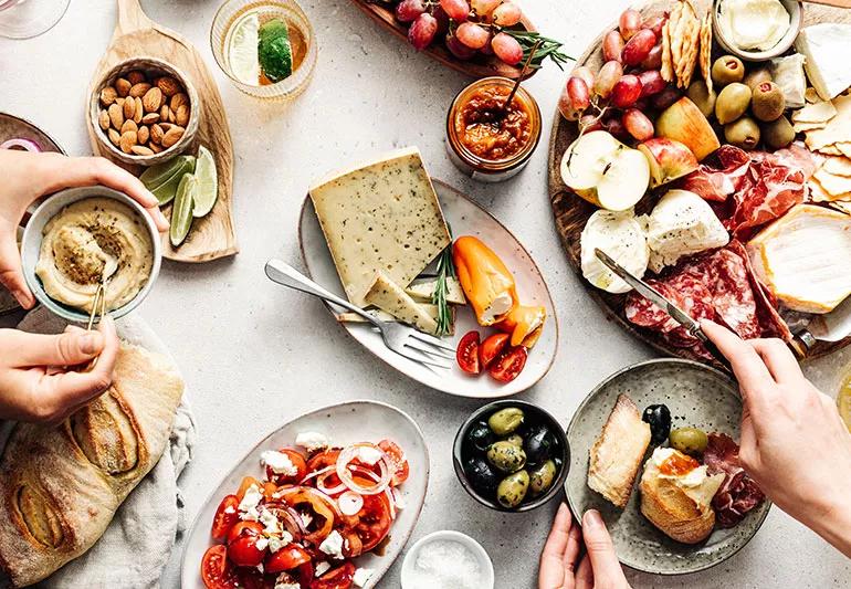 A table full of dishes like a charcuterie board, olives, nuts and bread