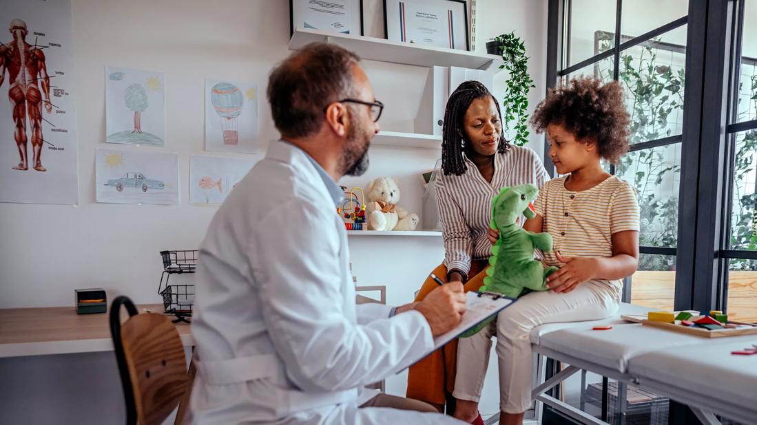 Caregiver and child with doctor in kid-friendly pediatrician office