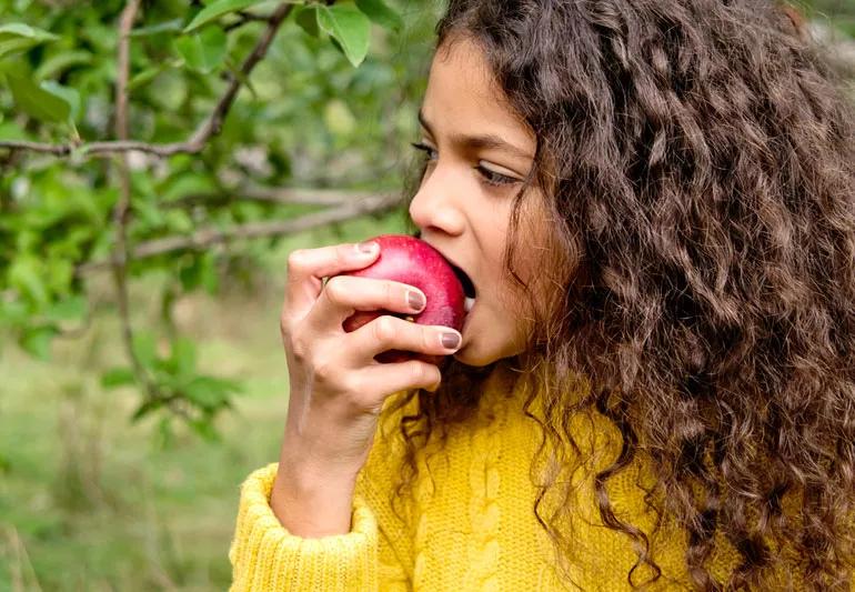 girl taking a bite of an apple