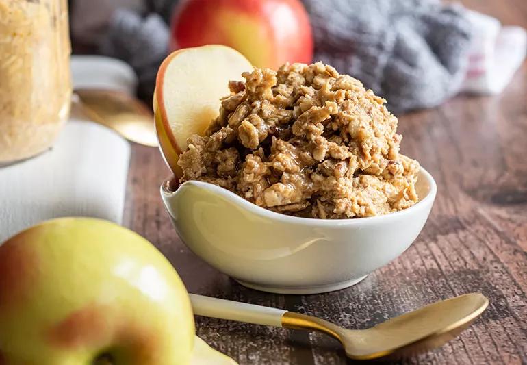 A bowl of granola with a big slice of apple
