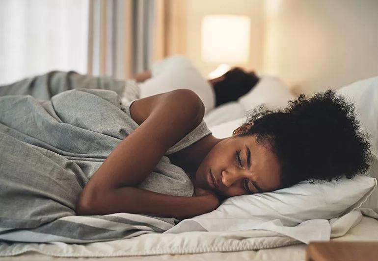 Two people lay on opposite sides of the bed, with one person crying and upset.