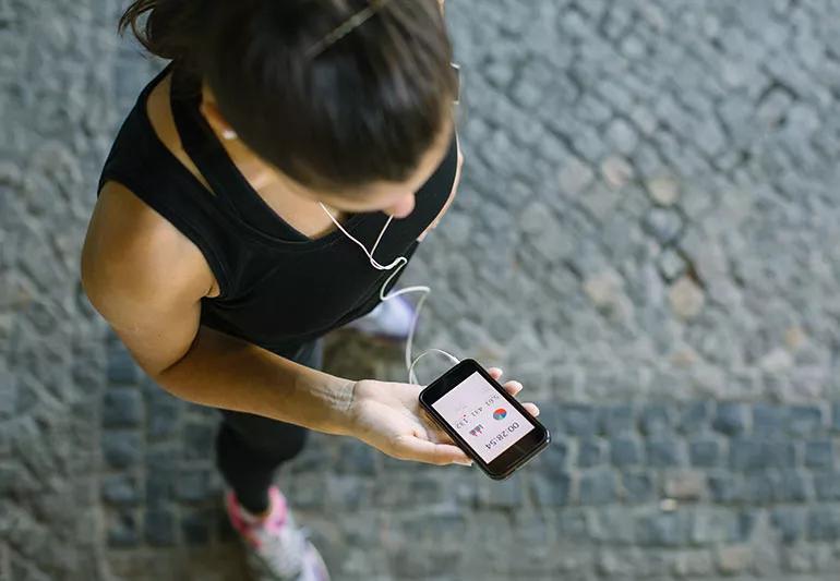 Someone wearing gym gear checks their heart rate using a smartphone.