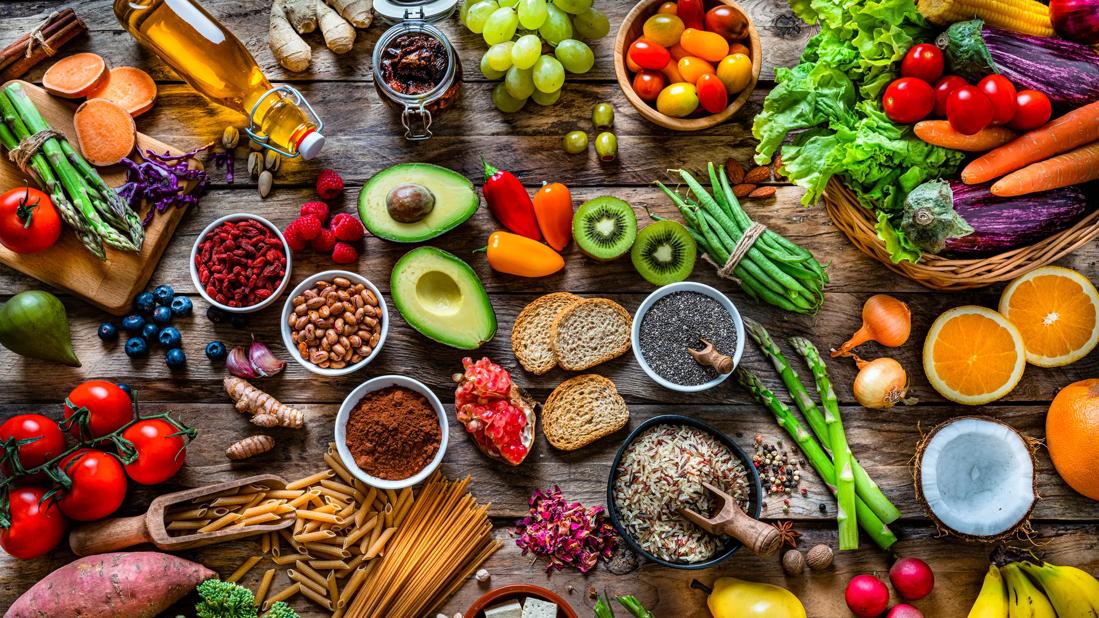 Table of assorted healthy foods, like fruits, veggies, grains, nuts and olive oil