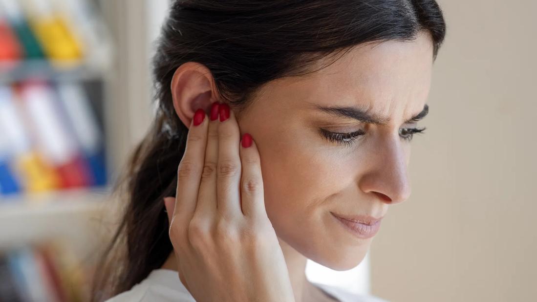 Person frowning, with hand held up to their ear