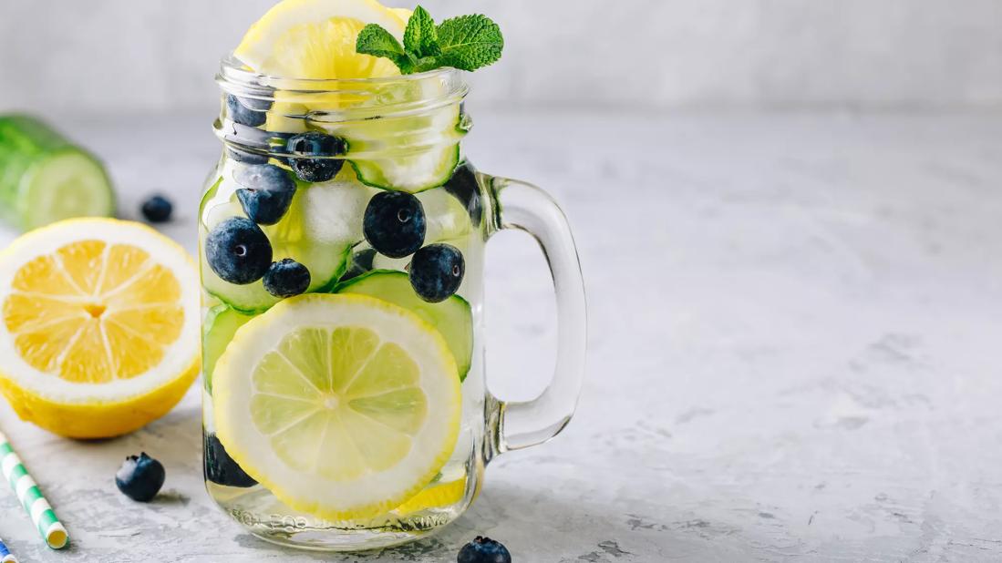Water in mason jar mug with cucumber, blueberries and lemon
