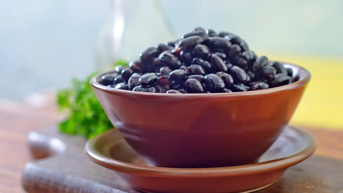 Bowl of cooked black beans on plate on cutting board