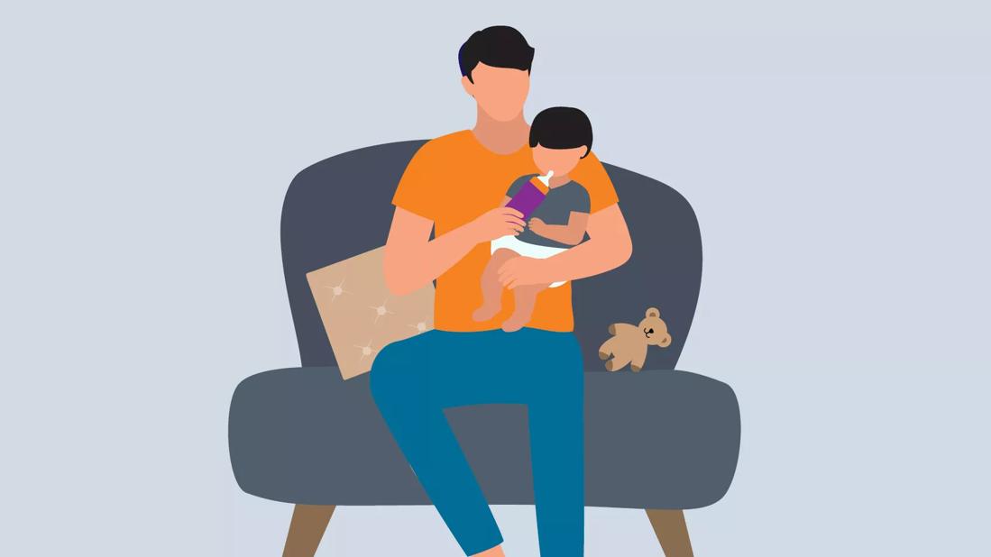 Parent holding baby and giving bottle to baby on a chair