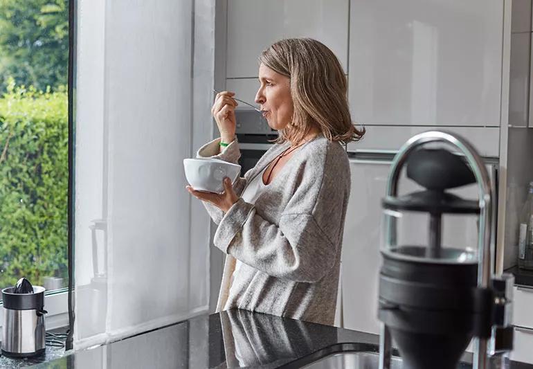 menopausal woman eating breakfast in kitchen