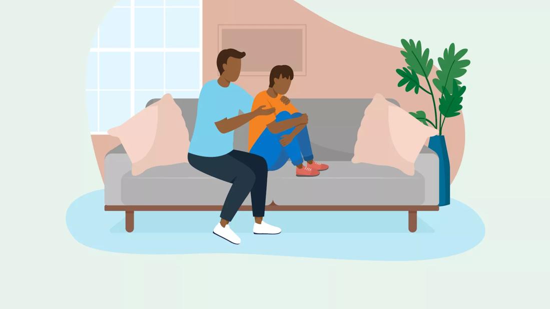 Parent consoling child on sofa.