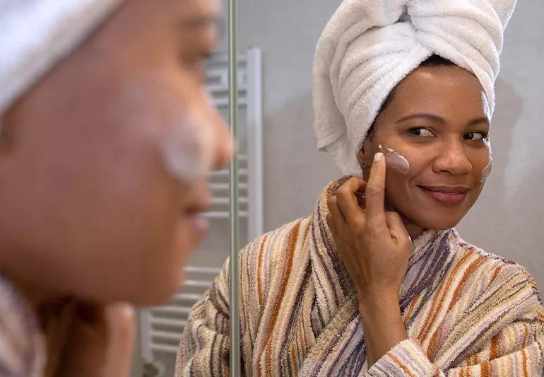 Person applies moisturizer as part of their skin care routine after a shower.