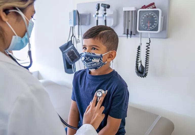 Physician listens to child's heart beat with stethescope during officer appointment.