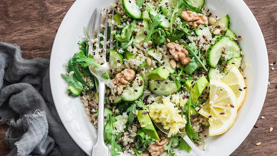 Flaxseed sprinkled on a salad in a white bowl on a dark wooden table