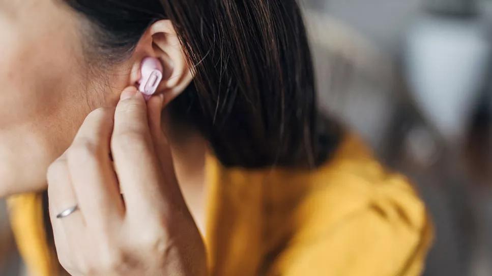 person adjusting ear bud in ear