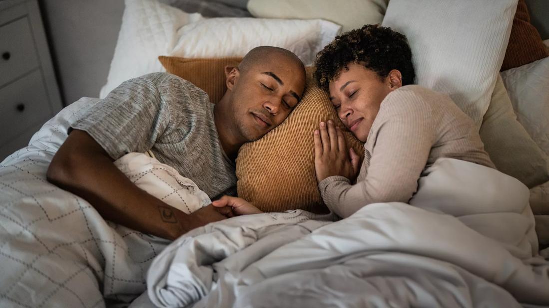 Happy couple sleeping in bed together, holding hands