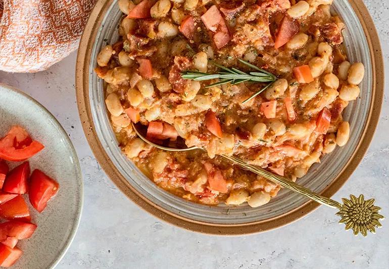 A bowl of Great Northern beans with tomatoes and herbs