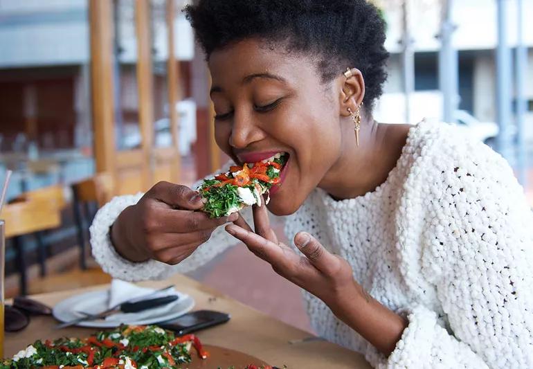 young woman eating vegetable pizza