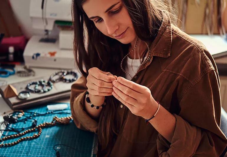A person sitting in a studio making jewelry