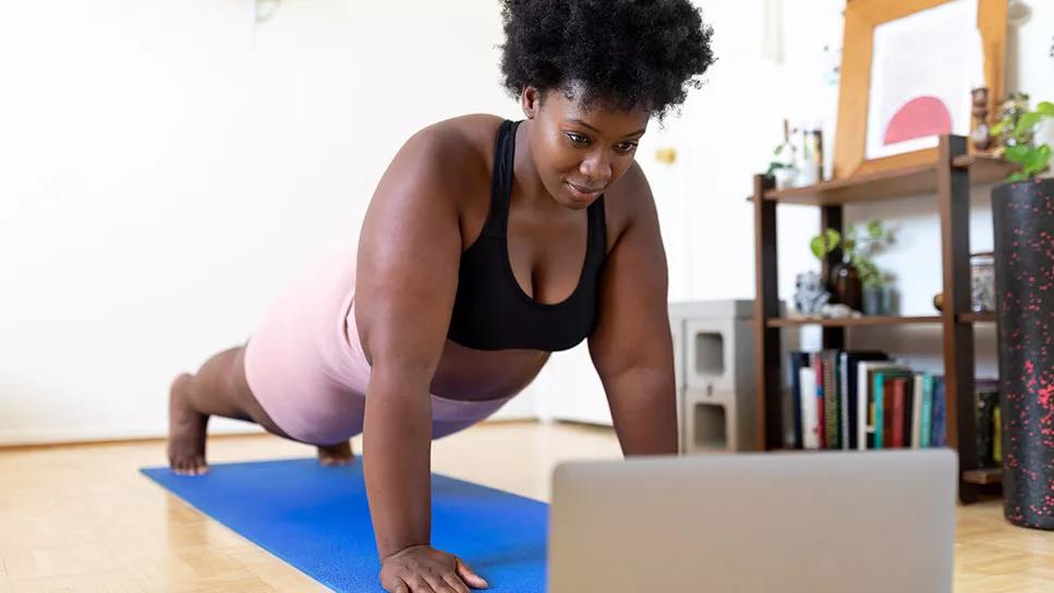 female doing a push up while looking at laptop