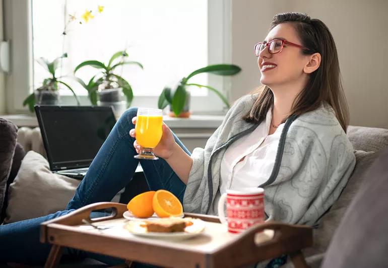 Woman eating healthy breakfast with eggs, oranges and tea