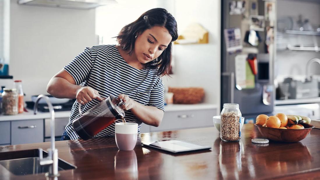 Person pouring coffee from a French press in their kitchen