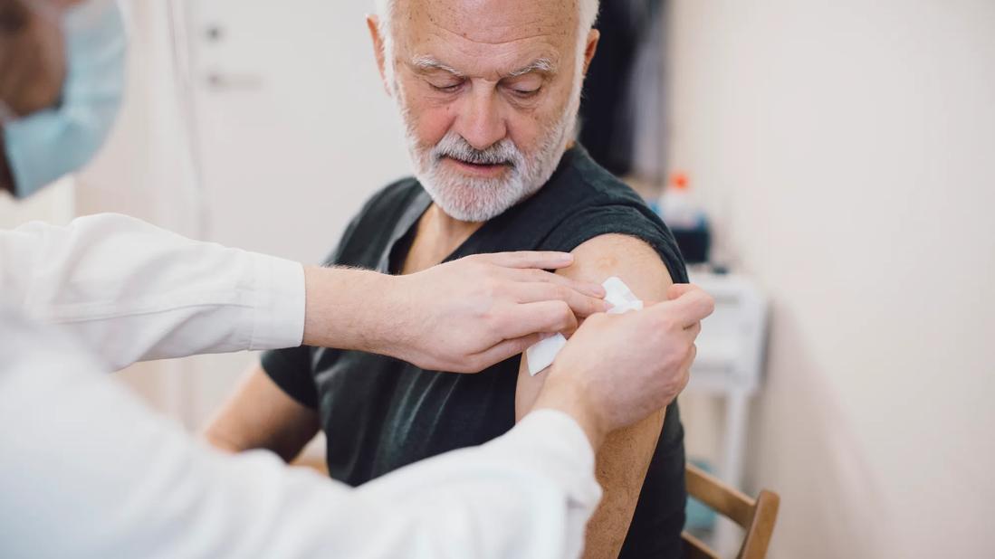 Healthcare provider applying a bandage on arm of person after injecting a shot