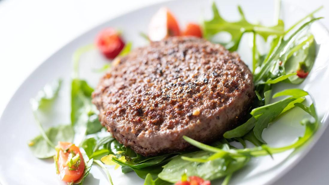 Turkey burger with cilantro, scallions and ginger on be of mixed greens