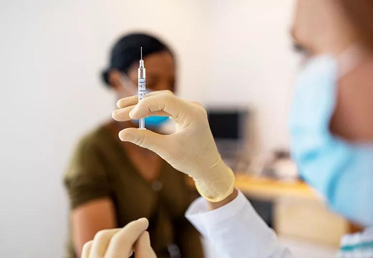 A healthcare provider holding a shot in their hands like they are going to administer a vaccine