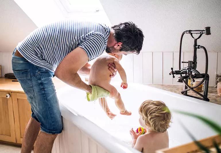 Parent bathing 2 toddlers.