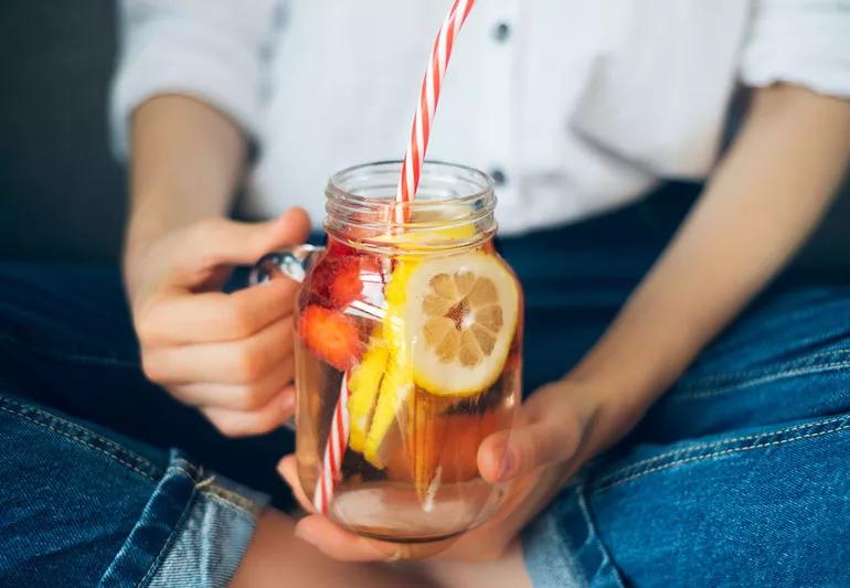 Woman drinking water filled with fruit