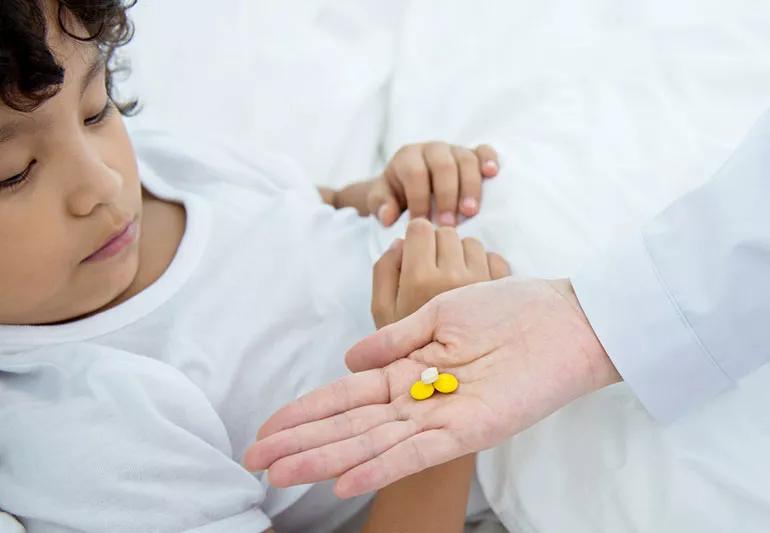 sick child taking medicine from parent