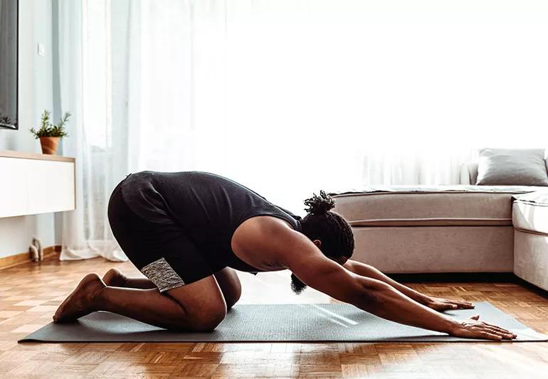 Person doing yoga stretche on mat in living room