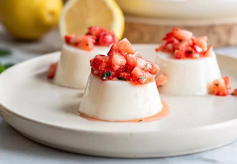 A plate with three servings of vanilla panna cotta topped with strawberries