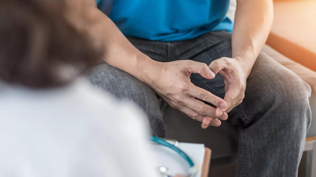 Man in clinical setting speaking with doctor