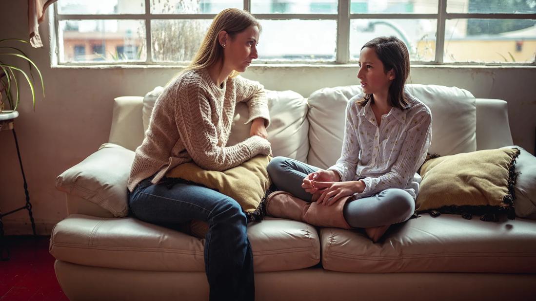 Adult having a serious talk with a child in living room on a couch