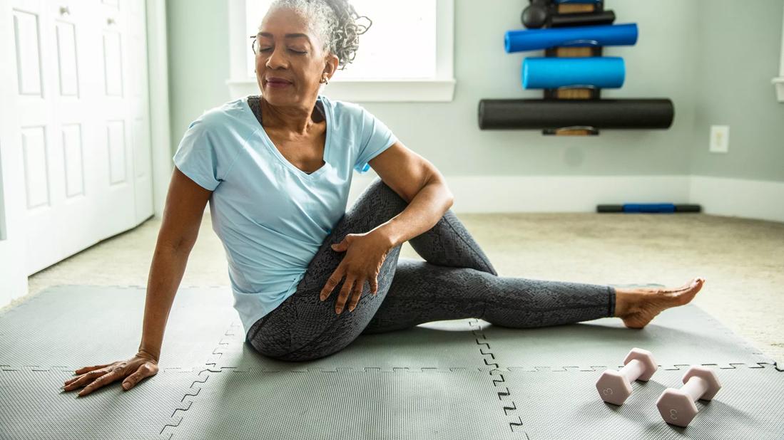 Person stretching on floor mats in their home gym area