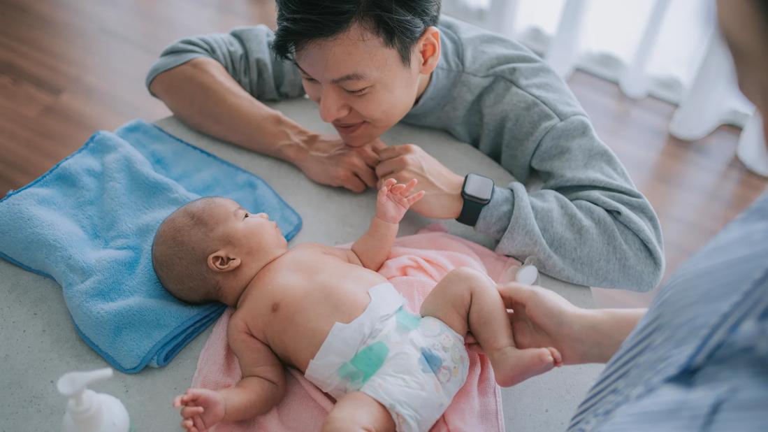 Caregivers adoring baby in diaper on diaper changing table